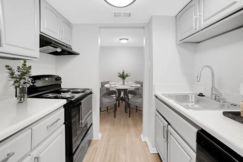 A kitchen with white cabinets and black appliances.